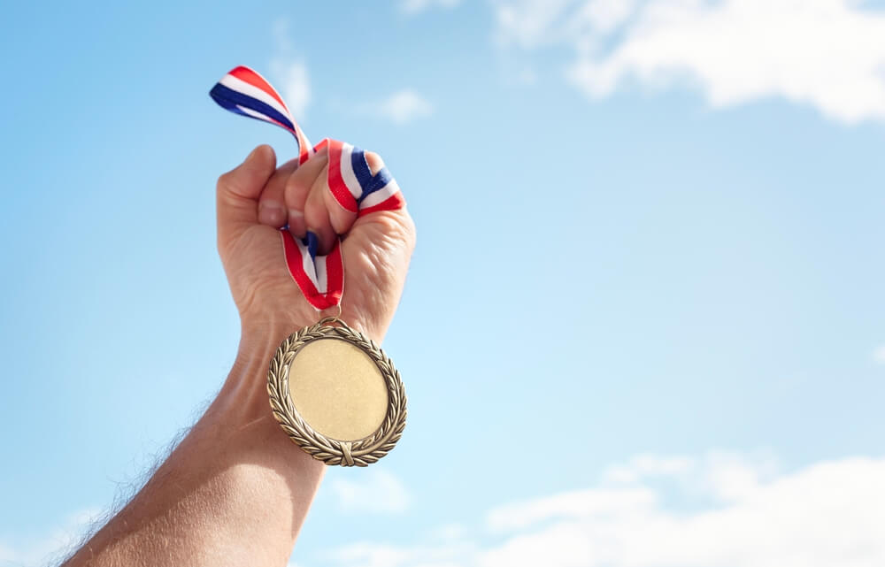 Złoty Medal trzymany przez mężczyznę po wygranej